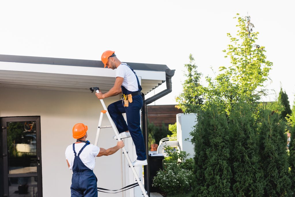 Two workers inspecting gutter system